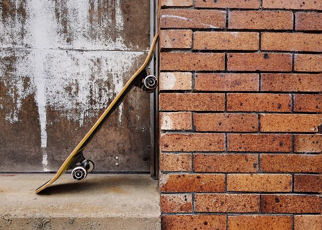 Picture of a skateboard leaning against a brick wall.